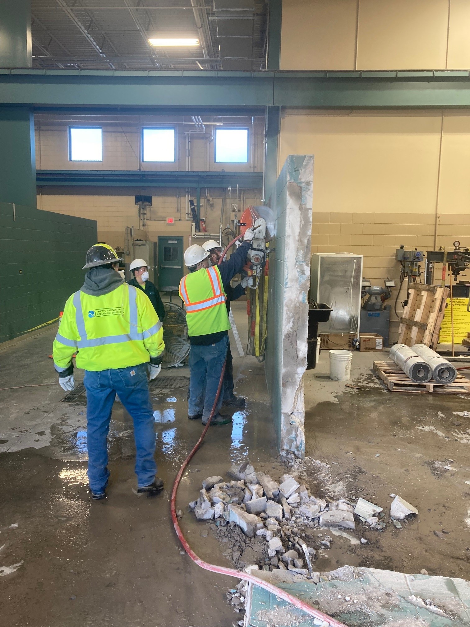 metro employees safely removing a brick wall while wearing personal protective equipment