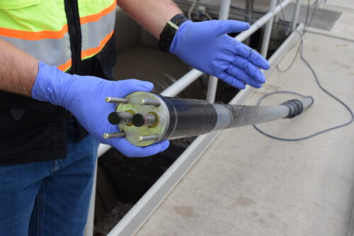 A Metro employee pulls a pilot TSS probe from the RWHTF CaRRB Splitter Box. This probe is long and narrow with electrodes fitted to the end.
