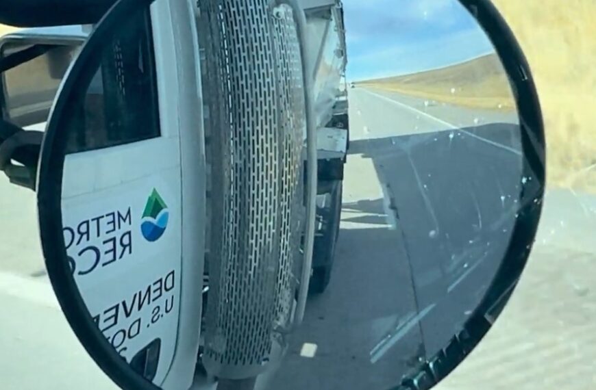 A side-view mirror reflecting the METROGRO truck while driving