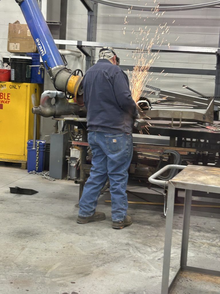 A worker grinds metal to make a custom fixture.
