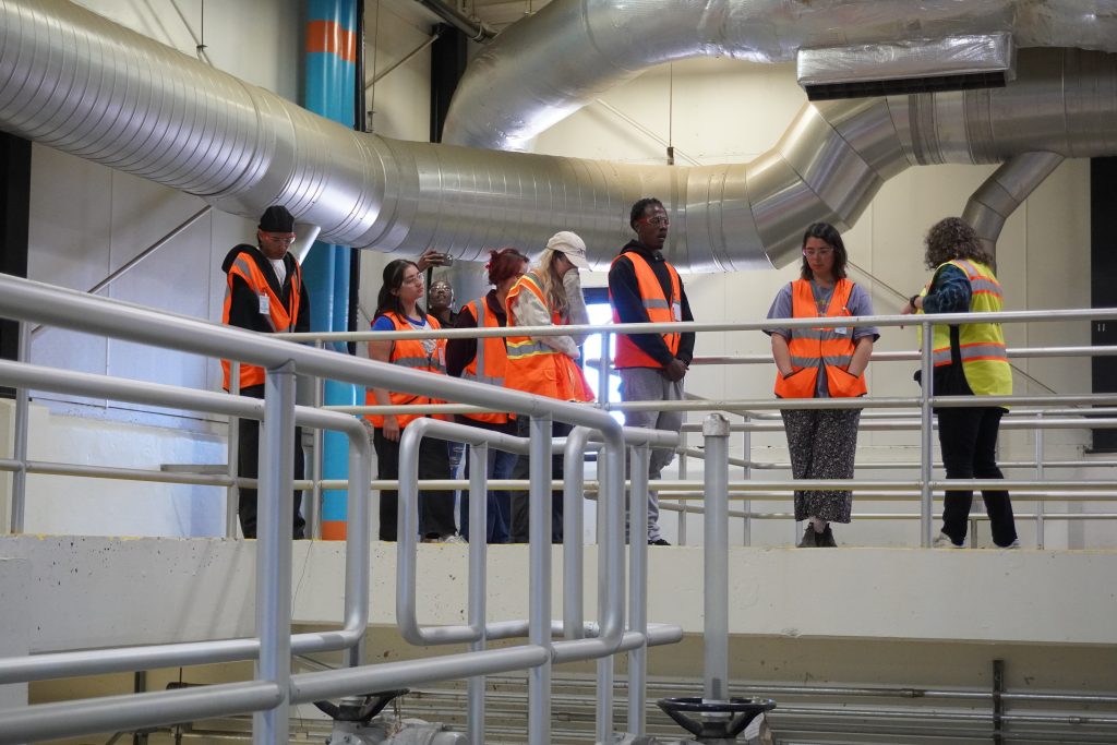 A group of 7 young adults tour the bar screen area