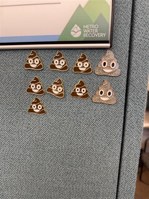 9 Poop emoji pins are stuck onto Veronica's cubicle by her name tag

