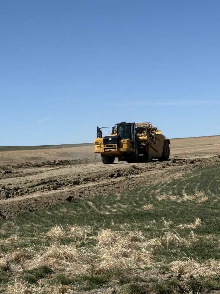 a road scraper vehicle grates a dirt road. 